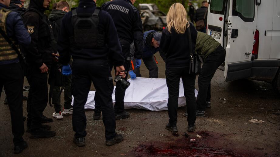 Polisanställda för bort kroppen av en död kvinna efter den ryska robotattacken.
