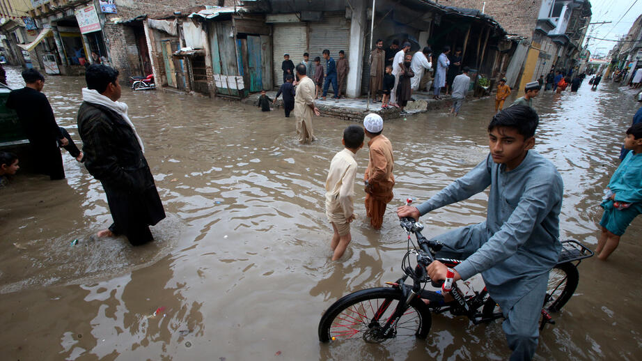 Människor vadar i vatten på en översvämmad gata i Peshawar i Pakistan tidigare i veckan. 
