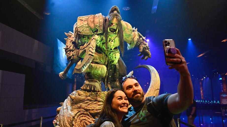 Två fans tar en selfie med orken Grom Hellscream, en karaktär i spelet World of warcraft.