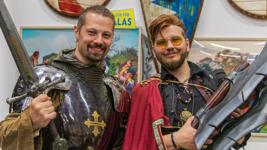 Olof eller Kapten Gaius Drakvän (vänster) står bakom sin monter och visar upp svärd till försäljning.