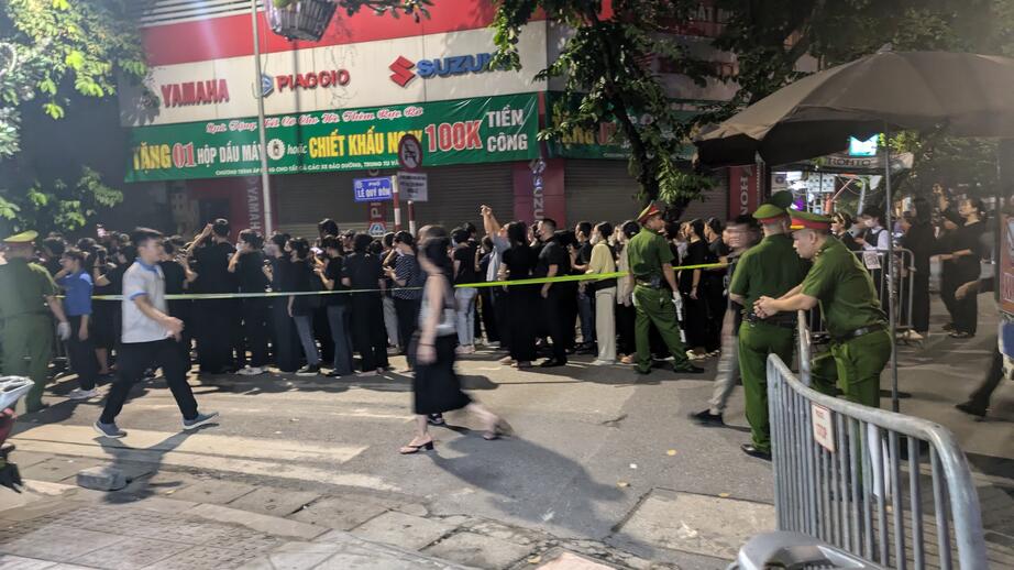 Svartklädda Hanoi-bor står i den långa kön till Trongs begravning. Vakterna bär uniform.