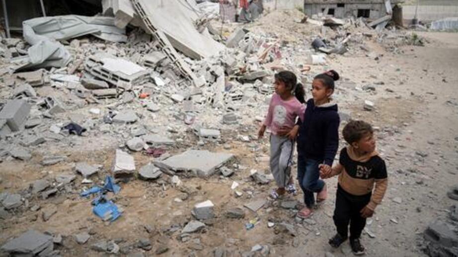 Tre barn passerar ett sönderbombat hus i Gaza.