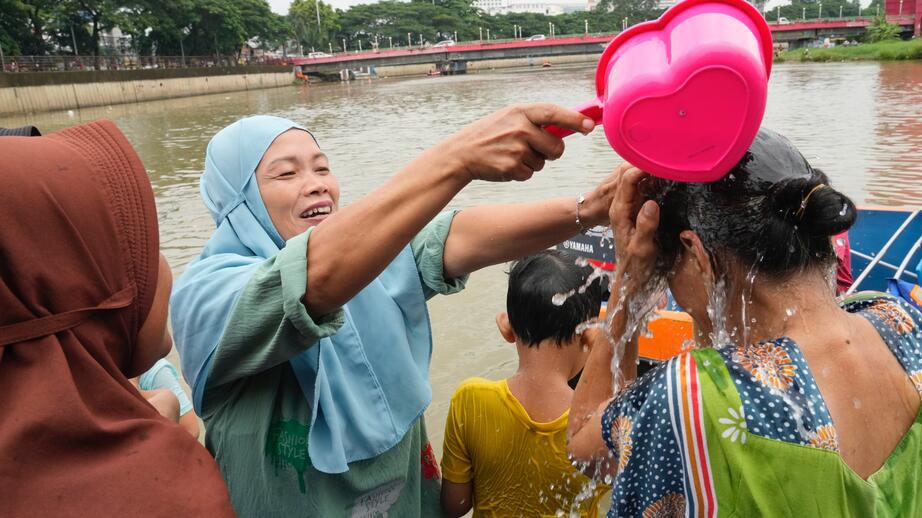 Människor badar i floden Cisadane inför den heliga fastemånaden Ramadan i Tangerang, Indonesien, 2024.