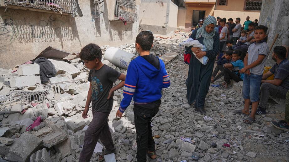 Palestinier går runt i resterna av ett hus i Jabalia i norra Gaza. Det ska ha träffats av israelisk eldgivning under söndagen. Enligt AP dog minst tio personer.
