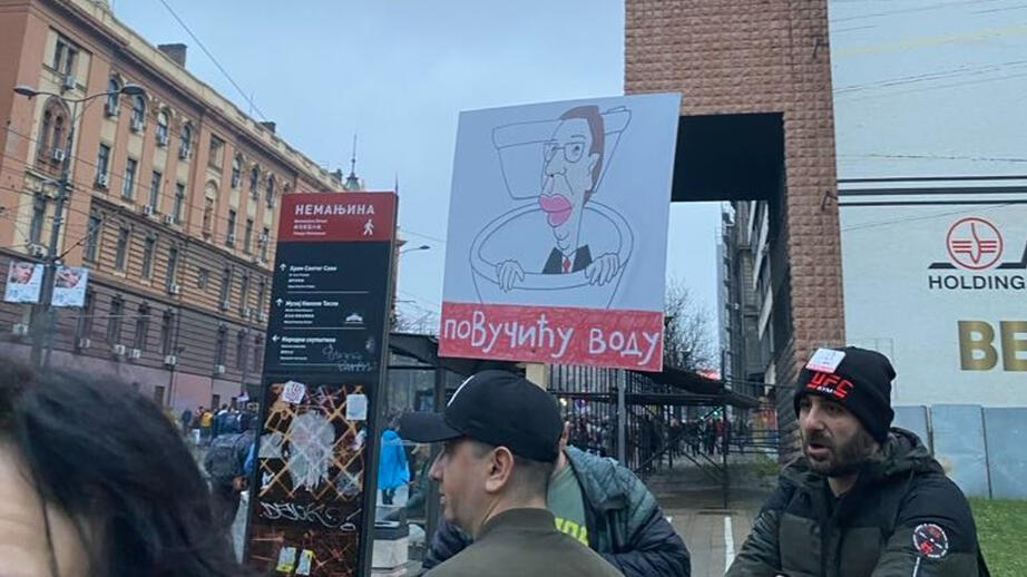 En man protesterar med en karikatyr av president Aleksander Vucic. 